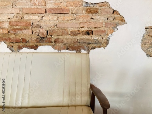 vintage beige leather with real wood sofa and white cement wall that has been chipped off to reveal the old red bricks inside the wall