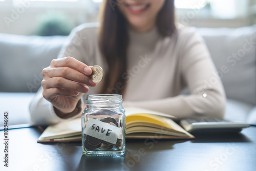Fotografi Saving money wealth concept, asian young business woman hand putting coin into jar for saving cost, cash finance planning to spend enough money on her income for save money, payment tax, investing