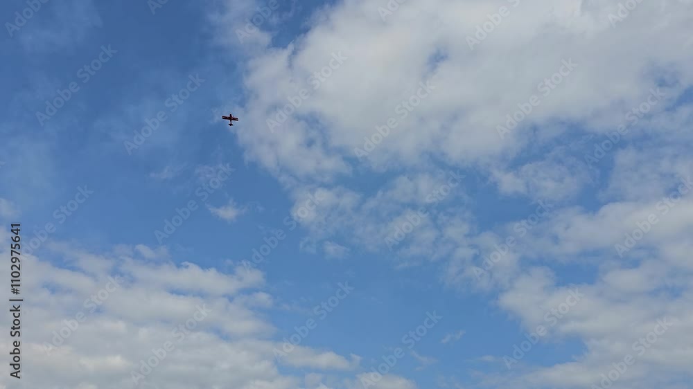 A stunt plane glides through the sky with its engine cut off, appearing uncontrolled against a backdrop of blue skies and scattered clouds. A stunt plane glides through the sky with its engine cut off, appearing uncontrolled against a backdrop of blue skies and scattered clouds.