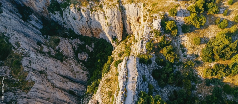 Fototapeta premium aerial view of rugged cliff landscape with greenery and rocky formations under bright sunlight