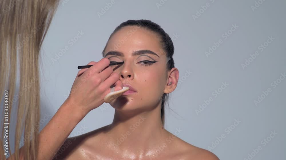 Make-up artist applies makeup with cosmetic brush. Beauty visage. Makeup master with young beauty model girl. Make up in process. Young beautiful asian woman applying make-up by make-up artist. Make-up artist applies makeup with cosmetic brush. Beauty visage. Makeup master with young beauty model girl. Make up in process. Young beautiful asian woman applying make-up by make-up artist.