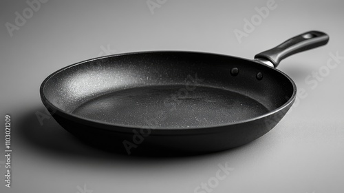 Non-stick frying pan with a smooth surface isolated on a minimalist grey background for cooking and kitchenware concepts. photo