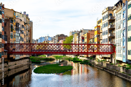 Colorful buildings along Onyar River with red bridge photo