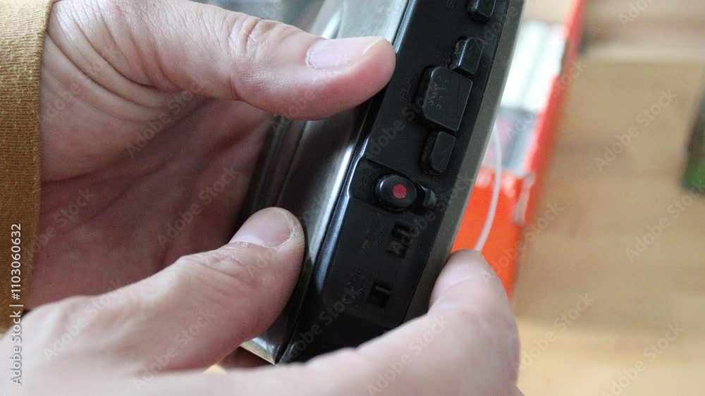 A senior Asian man inserting a cassette tape into a cassette player to listen to music. A senior Asian man inserting a cassette tape into a cassette player to listen to music.