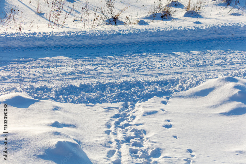 Obraz premium A snow covered road with tire tracks in the snow