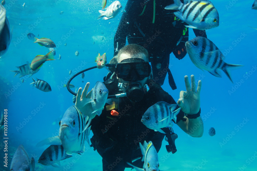 Scuba diver makes okay sign with his hands underwater during scuba diving at coral reef