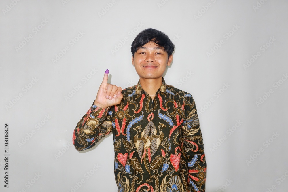 Fototapeta premium A man shows his little finger after voting for the presidential or regional head election in Indonesia using batik on a white background