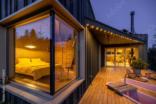 Evening glow from a cozy bedroom window with a pet dog looking outside. The wooden deck leads to an inviting interior illuminated by soft, ambient lights