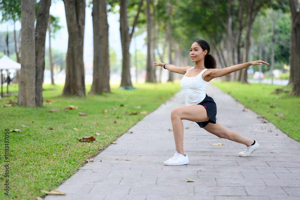 African American woman doing leg lunge exercise on a park pathway African American woman doing leg lunge exercise on a park pathway