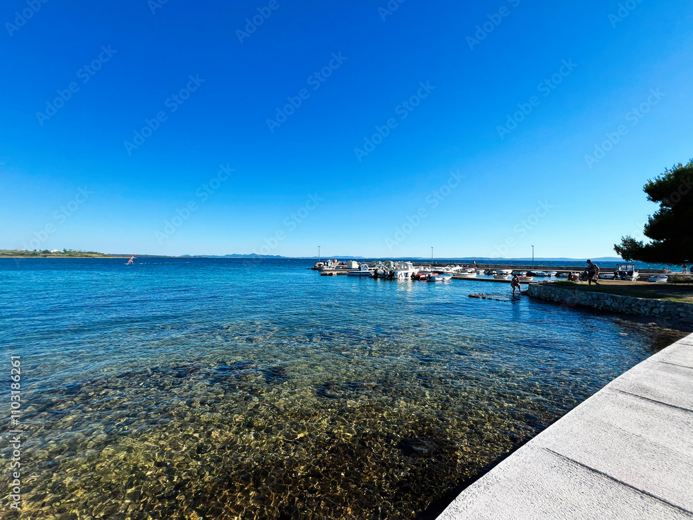 Fototapeta premium Serene coastal view with boats under a clear blue sky