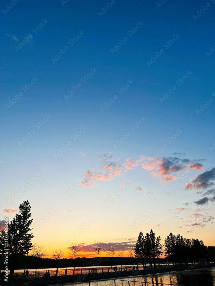Fototapeta premium Tranquil lakeside sunset with silhouettes and vibrant sky