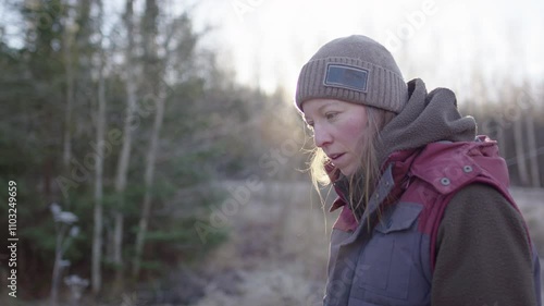 Handywoman backlit by sunrise dressed warmly on chilly morning taking breather