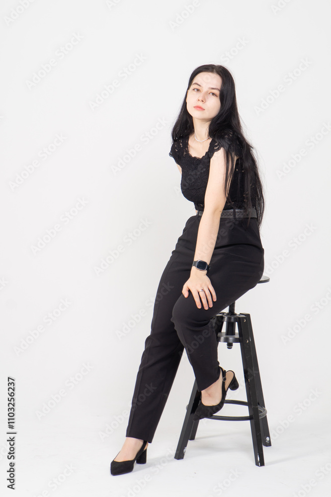 Fototapeta premium Cute young brunette girl sitting on a white background. Copy space