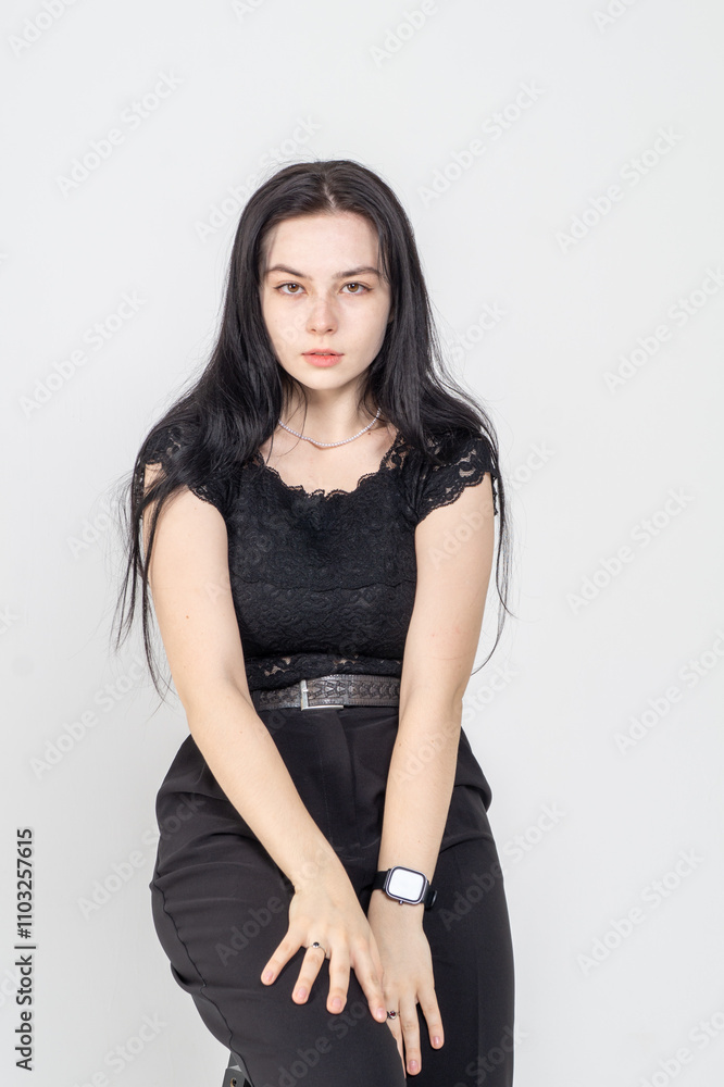Cute young brunette girl sitting on a white background. Copy space Cute young brunette girl sitting on a white background. Copy space