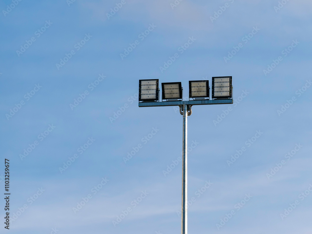 LED floodlights mounted on a high pole against a blue sky LED floodlights mounted on a high pole against a blue sky
