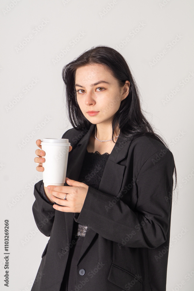Cute young brunette with a coffee cup on a white background. Copy space Cute young brunette with a coffee cup on a white background. Copy space