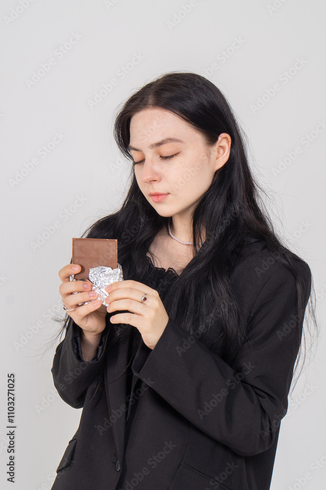 Cute young brunette with a chocolate bar on a white background. Copy space Cute young brunette with a chocolate bar on a white background. Copy space