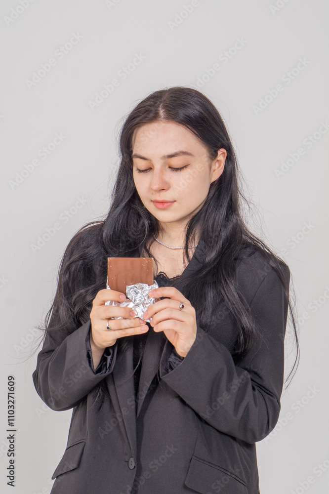 Cute young brunette with a chocolate bar on a white background. Copy space Cute young brunette with a chocolate bar on a white background. Copy space