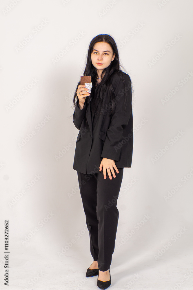 Cute young brunette with a chocolate bar on a white background. Copy space Cute young brunette with a chocolate bar on a white background. Copy space
