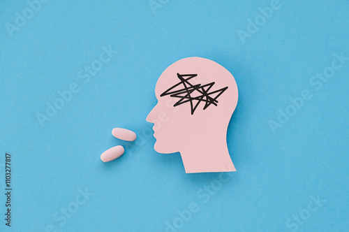 Mental health medication concept image with paper figurine of a head taking an antidepressant pill to cure depression with a table photo