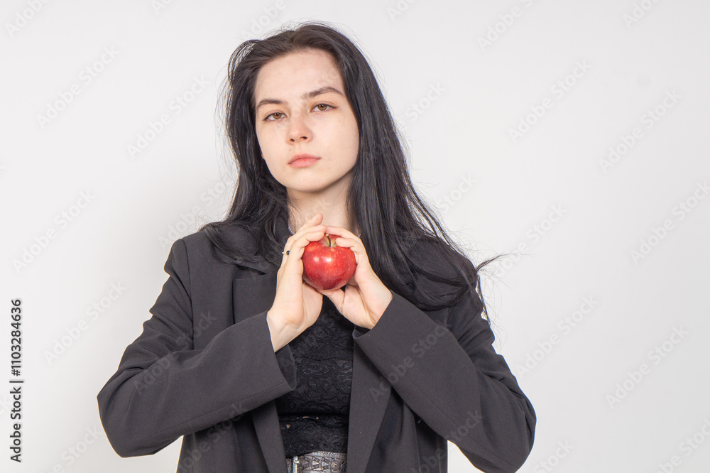 Young cute brunette girl with a red apple on a white background. Copy space Young cute brunette girl with a red apple on a white background. Copy space