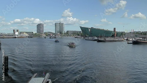 Boats sailing towards the canals in the centre of Amsterdam. In the background Nemo Science Museum. Amsterdam. The Netherlands.