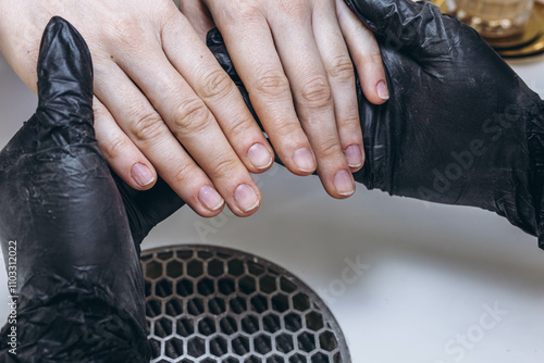 Manicure master, working in the beauty salon shaping the nails of a young female client photo