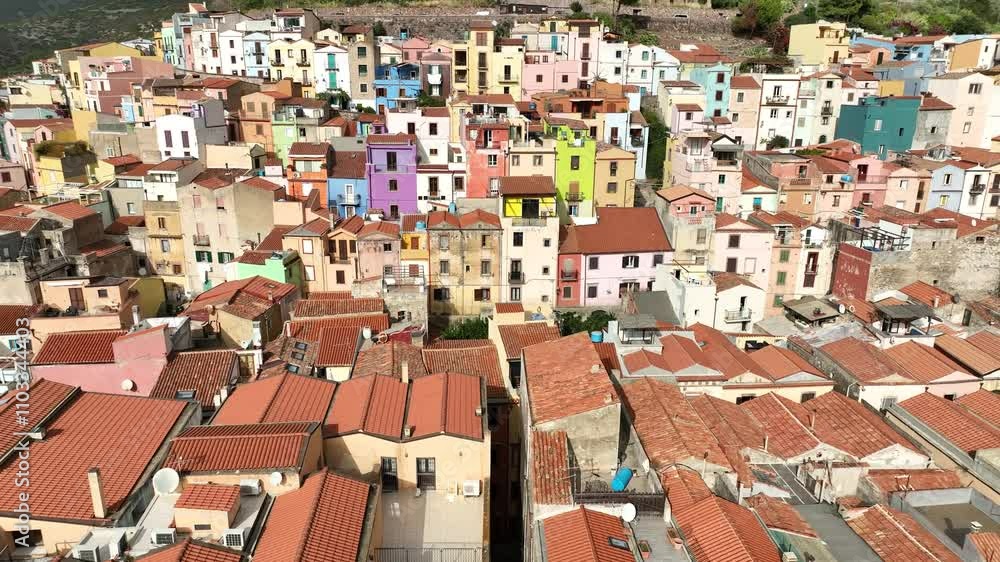 Aerial view of picturesque colorful houses and rooftops with a medieval fortress against a scenic mountainous backdrop, Bosa, Italy. Aerial view of picturesque colorful houses and rooftops with a medieval fortress against a scenic mountainous backdrop, Bosa, Italy.