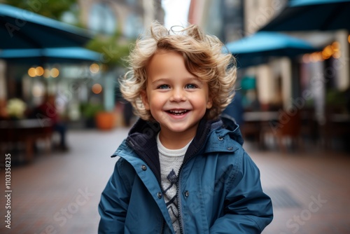 Portrait of a cute little boy in a blue jacket on the street.