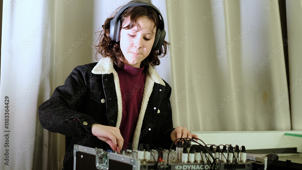 A young girl wearing headphones operates a sound mixer, smiling as she adjusts the controls. This image portrays creativity, enthusiasm, and engagement in a musical or technical activity. A young girl wearing headphones operates a sound mixer, smiling as she adjusts the controls. This image portrays creativity, enthusiasm, and engagement in a musical or technical activity.