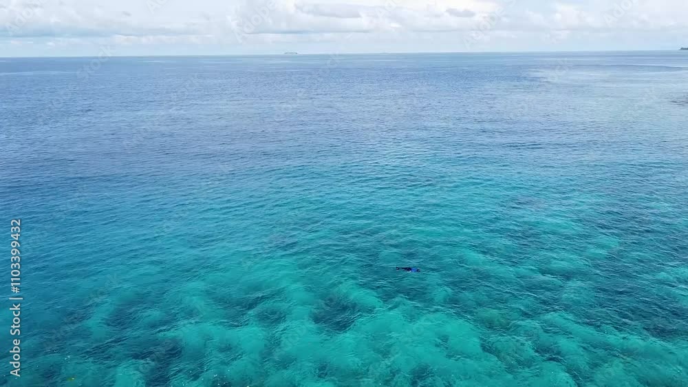 Flying over ocean of tropical island of Pulau Weh with turquoise blue ocean water, coral reef, and person snorkeling in Sabang, Sumatra in Indonesia