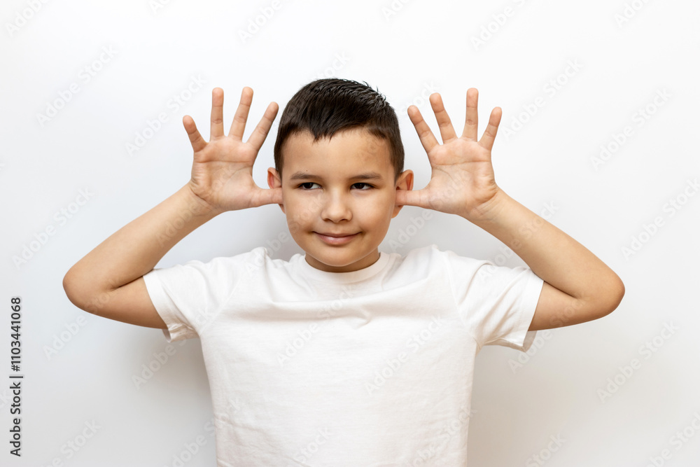 The guy grimaces, showing his ears with his palms. Sincere children's emotions. The guy grimaces, showing his ears with his palms. Sincere children's emotions.
