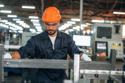 Metal pieces, standing. Man is working in the modern factory