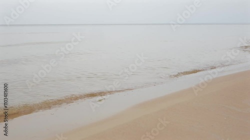 Small waves on the sandy Baltic Sea shore gently touch the beach.