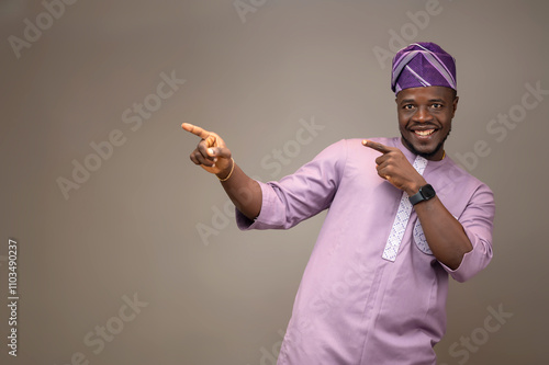 Nigerian Man in Native Attire with a Happy Expression Pointing Excitingly Towards a Direction photo