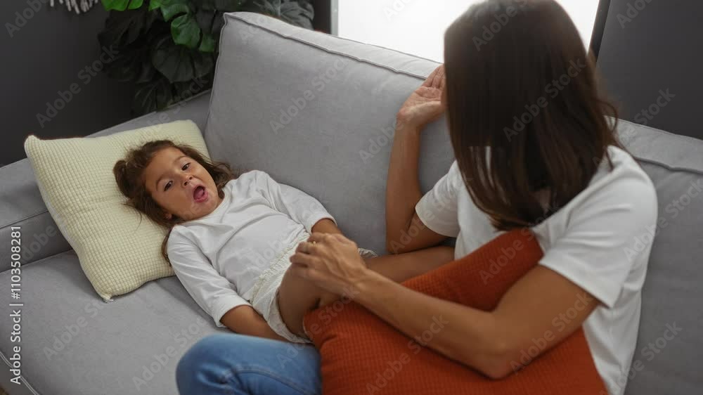 Woman relaxing with daughter on sofa in cozy home setting, highlighting family bond in a peaceful indoor environment. Woman relaxing with daughter on sofa in cozy home setting, highlighting family bond in a peaceful indoor environment.