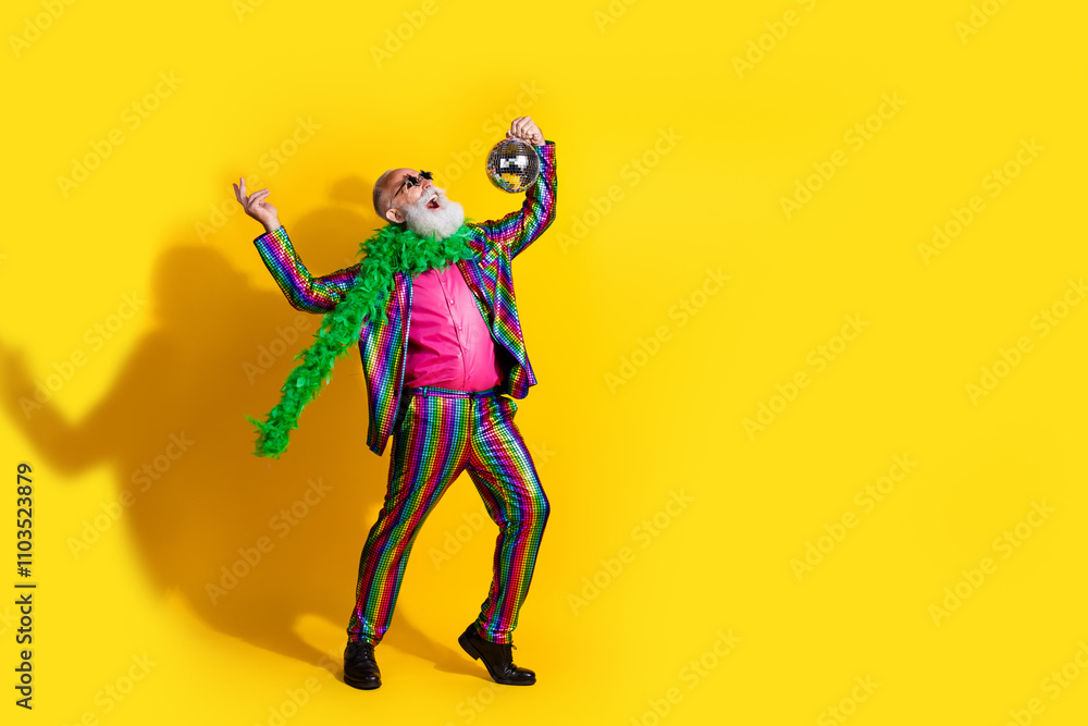 Full size photo of excited old man showman hold discoball dance wear glamour striped bright clothes boa sunglass isolated yellow background Full size photo of excited old man showman hold discoball dance wear glamour striped bright clothes boa sunglass isolated yellow background