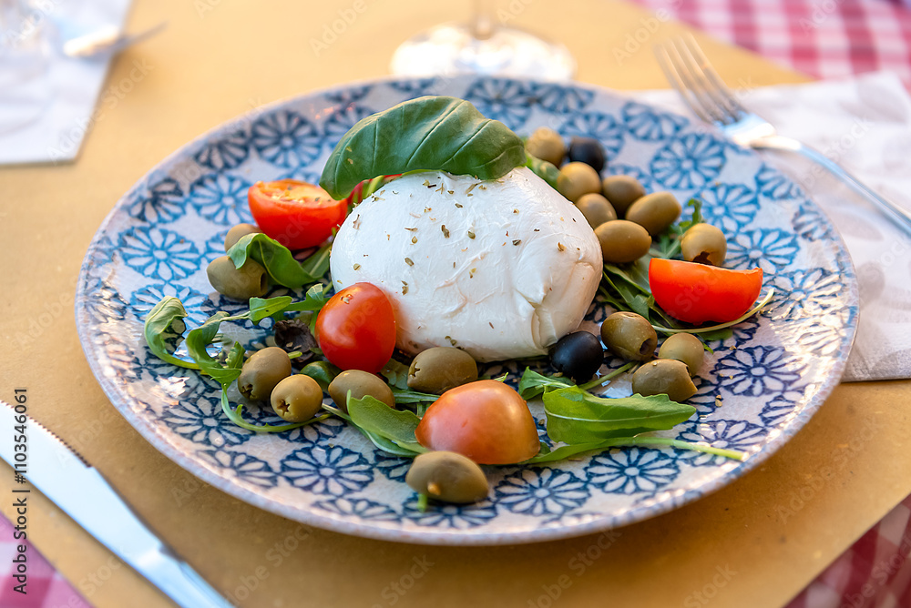 Plate with Italian Bufala mozzarella, tomatoes and olives. Serving in a restaurant