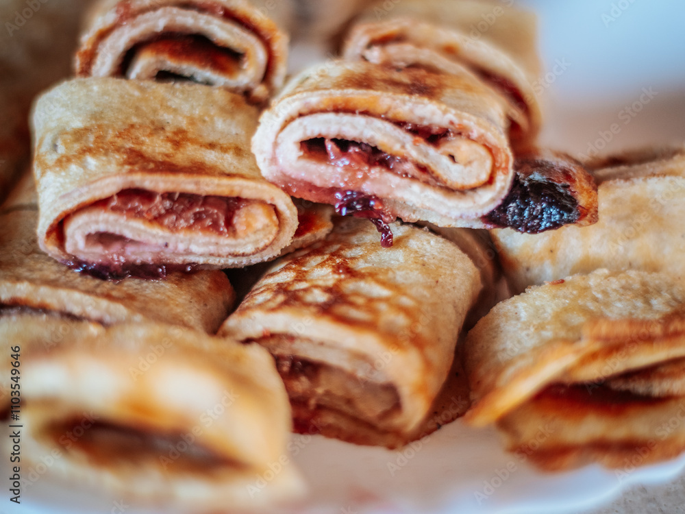 A close-up view of freshly cooked golden brown rolled pancakes, some sliced to reveal the filling. The texture and crispy edges highlight their appetizing appearance. A close-up view of freshly cooked golden brown rolled pancakes, some sliced to reveal the filling. The texture and crispy edges highlight their appetizing appearance.
