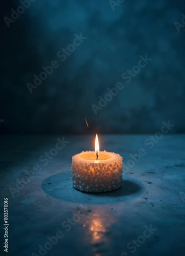 a single candle is lighten up on a dark blue table