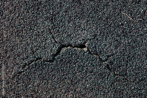 Detailed image of a green and black cracked asphalt road surface.