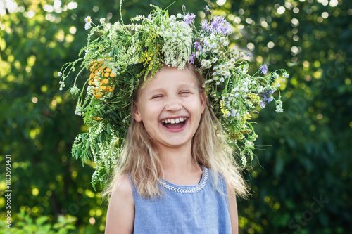 Summer Holiday on Nature. Happy Child Little Girl Having Fun Smiling with Flower Wreath on Green Nature Background. Happy Emotions in Summer. photo