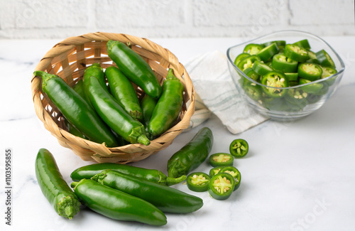 Sliced jalapeno pepper in wooden bowl isolated on white background. Green chili pepper with full depth of field. photo