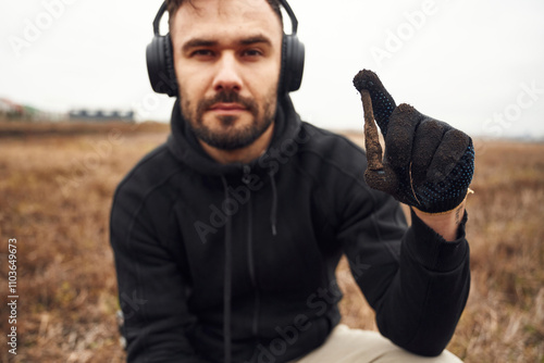 Man sapper in headphones is holding old bullet that he found in the field photo