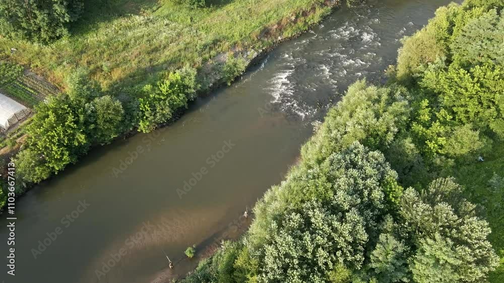 Scenic view of a winding river surrounded by lush green trees and fields in a rural area during daylight hours Scenic view of a winding river surrounded by lush green trees and fields in a rural area during daylight hours