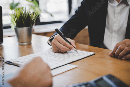 Fototapeta Naklejka Na Ścianę i Meble -  businessman sitting at desk holds pen signing contract paper, lease mortgage, employment hr or affirm partnership