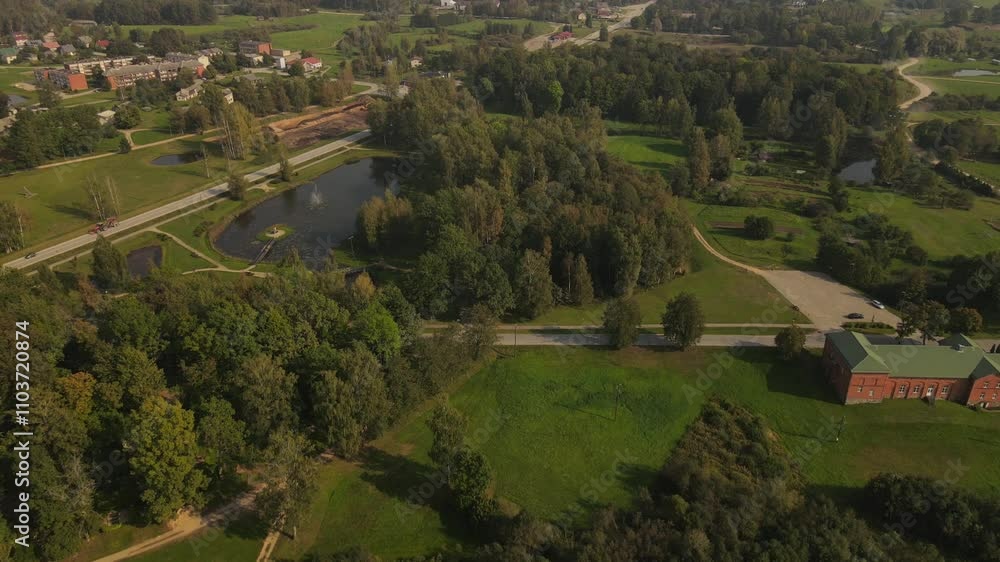 A picturesque drone view of the small town of Vecpiebalga, featuring lush greenery, quaint buildings, and scenic landscapes during summer's vibrant bloom.
