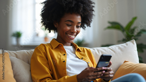 Happy black woman using credit card and phone for online shopping at home: Mobile banking and fintech solutions