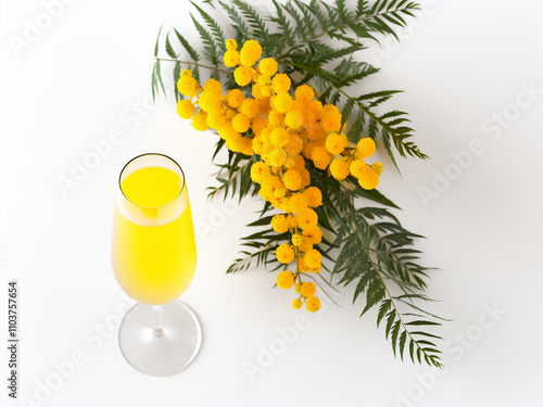 Top view of mimosa flowers in a glass vase on a white surface