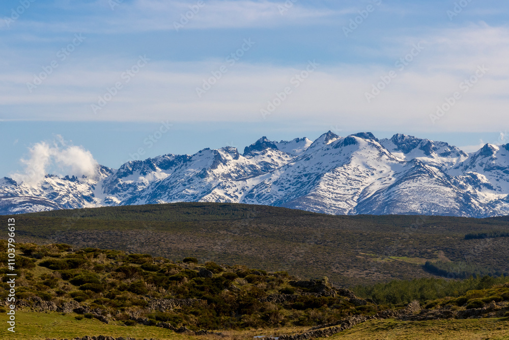 Sharp, snow-capped mountain peaks, shaped by Quaternary glaciers, rise above green hills with meadows and shrubs. We are in the Sierra de Gredos, part of the Central System in Spain Sharp, snow-capped mountain peaks, shaped by Quaternary glaciers, rise above green hills with meadows and shrubs. We are in the Sierra de Gredos, part of the Central System in Spain